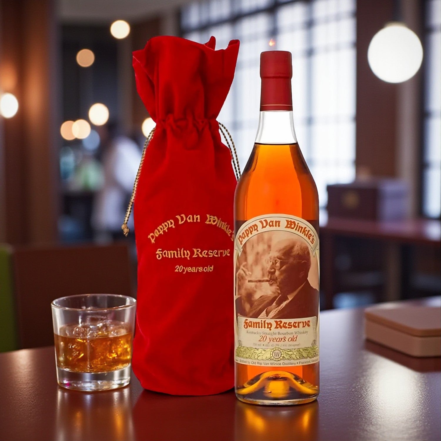 Engravable Pappy Van Winkle Family Reserve 20 Year Bourbon bottle with red velvet bag and glass of bourbon on wooden table – Top Bourbon lifestyle image
