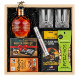 Blanton's Gold Edition Single Barrel Bourbon 700ml gift crate with gold horse stopper, crystal-cut old fashioned glasses, Royal Reserve whiskey stones set with tray, Montecristo Platinum cigar tube, Black Rifle Coffee Tactisquatch blend, Chocolove Almonds & Sea Salt dark chocolate bar, and Wonderful Pistachios in black crinkle paper on white background