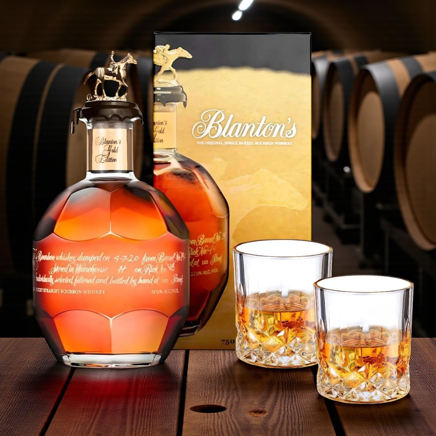 Engravable Blanton’s Gold Edition Single Barrel Bourbon Gift Set with bottle and glasses displayed against a bourbon barrel backdrop – luxury bourbon gift from Top Bourbon