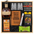 Blanton's Original Single Barrel Bourbon Top Shelf gift crate with bronze horse stopper, crystal-cut old fashioned glasses, Royal Reserve whiskey stones set with tray, faux-leather bourbon journal and pen set, Montecristo Platinum cigar tube, Black Rifle Coffee Tactisquatch blend, Chocolove Almonds & Sea Salt dark chocolate bar, and Wonderful Pistachios in black crinkle paper on white background