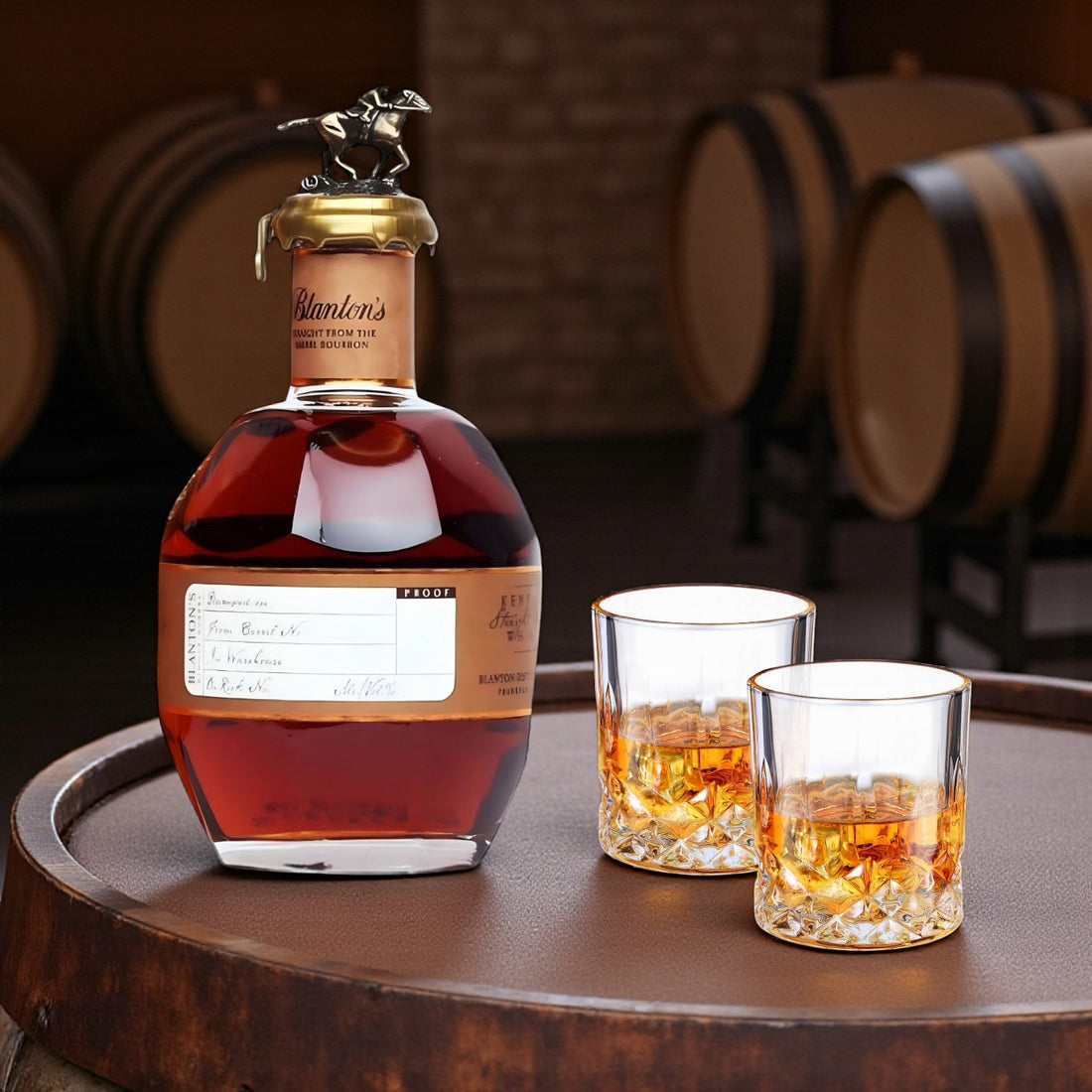 Engraved Blanton’s Straight From the Barrel Bourbon 700ml with two old-fashioned glasses on bourbon barrel in warehouse – Top Bourbon lifestyle image