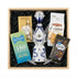 Clase Azul Reposado tequila gift crate with Ferrero Rocher chocolates, Gatsby dark chocolate, Chessmen cookies, trail mix and tequila flutes displayed in wooden gift crate by fireplace