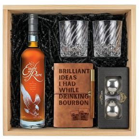 Eagle Rare 10 Year Kentucky Straight Bourbon Whiskey gift crate with orange label and white eagle illustration, crystal-cut old fashioned glasses with diagonal twisted swirl pattern, tan leather bourbon journal and pen set, and Stanley's XXL stainless steel whiskey balls all nestled in black zigzag crinkle paper inside wooden crate on white background