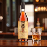 Engravable Old Rip Van Winkle 10 Year Bourbon bottle on polished bar beside glass of bourbon on ice – Top Bourbon lifestyle image